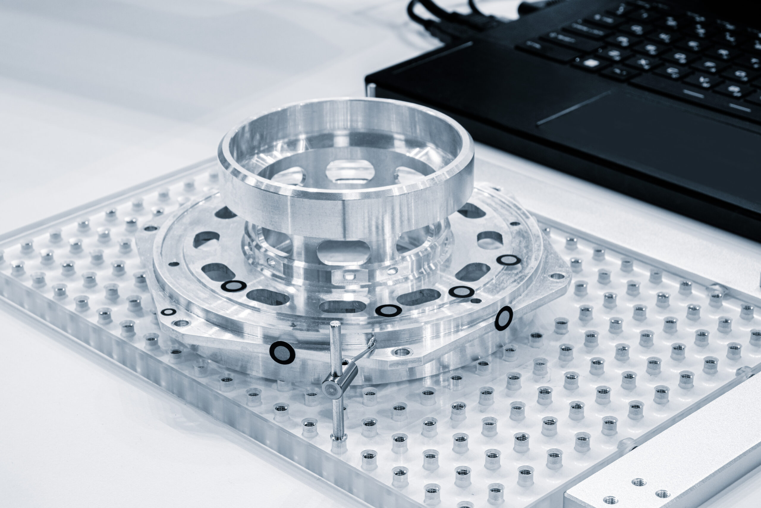 shiny metal part with multiple holes fixed on table of cnc metalworking machine, industrial metalworking concept background